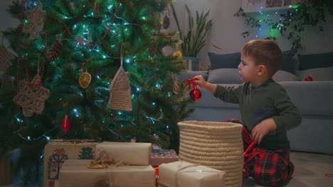 Boy-5-6-decorating-a-glass-ball-on-a-Christmas-tree-on-Christmas-Eve.-High-quality-4k-footage